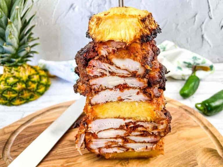 A grilled pineapple skewer with a fork on a cutting board.