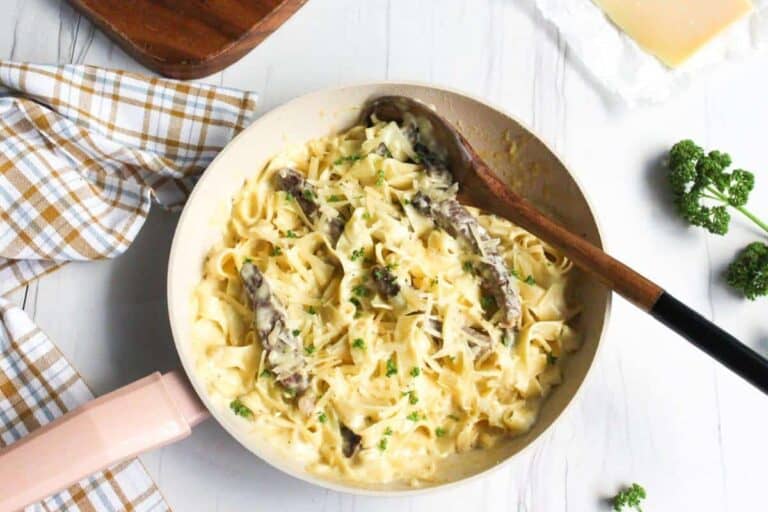 Alfredo steak pasta in skillet with wooden spoon.