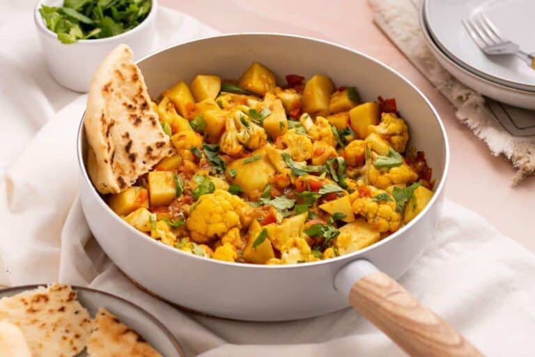 Aloo Gobi masala in skillet with naan bread.