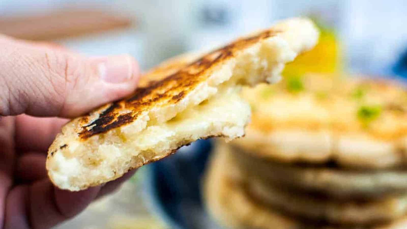 Close up shot of an arepa con queso split open to show the cheesy filling.