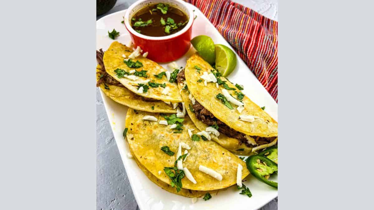 Birria Tacos on a plate with consomme.