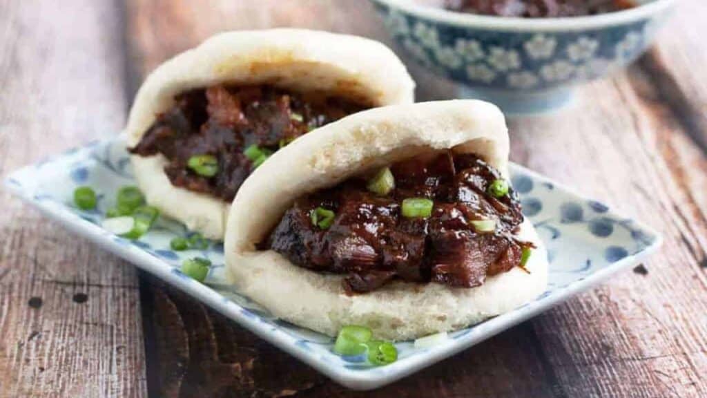 Low angle shot of two mantou buns filled with char siu filling.