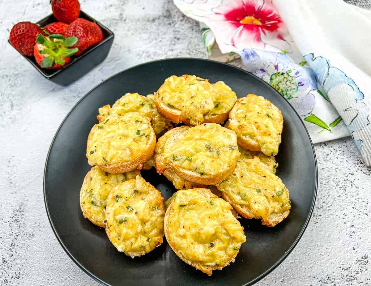 Bite-sized Cheese Toasties on a black plate.