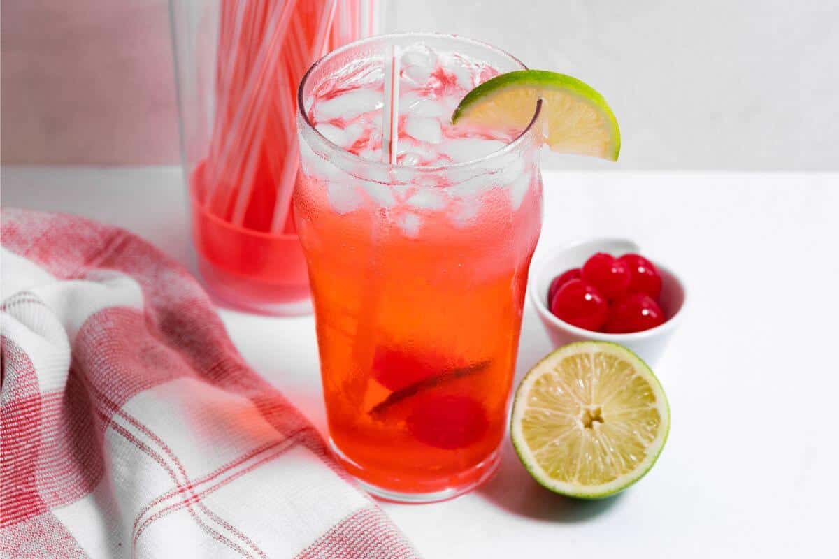 Cherry limeade in tall glass with lime wedge garnish.