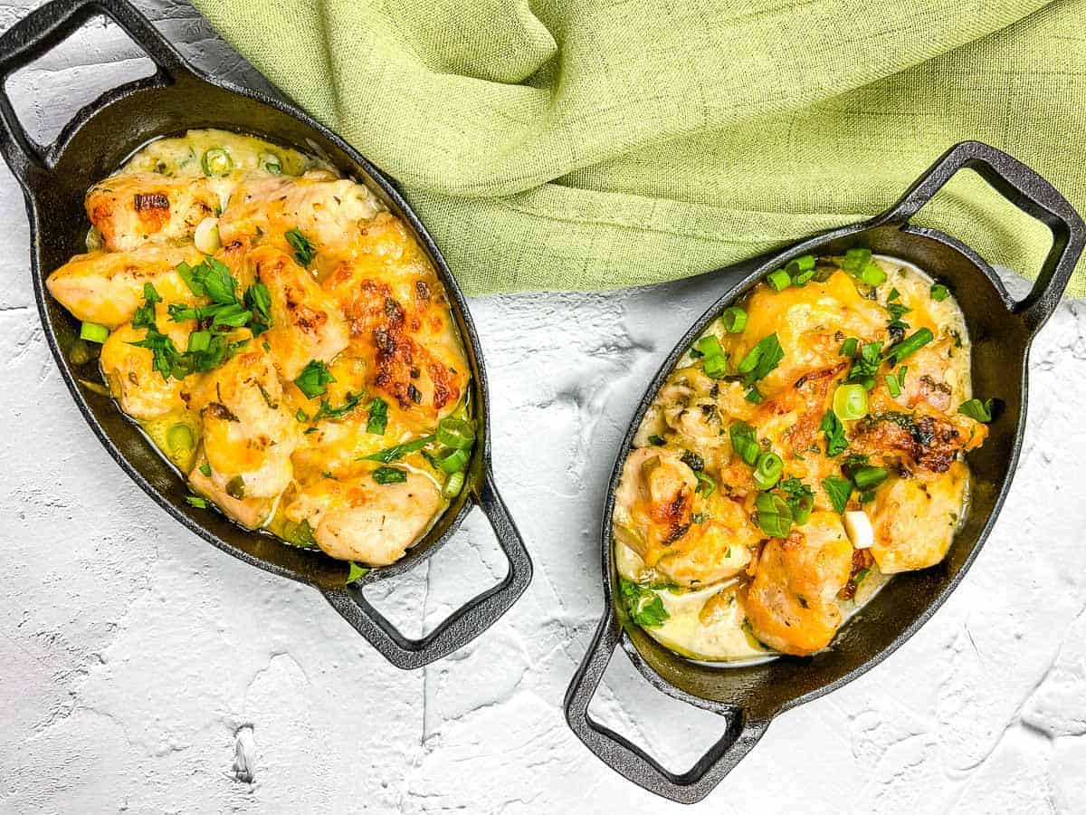 Two skillets filled with chicken and vegetables on a white background.