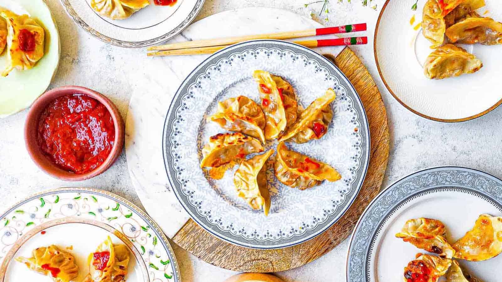 Overhead shot of chicken potstickers with chile paste on plates.