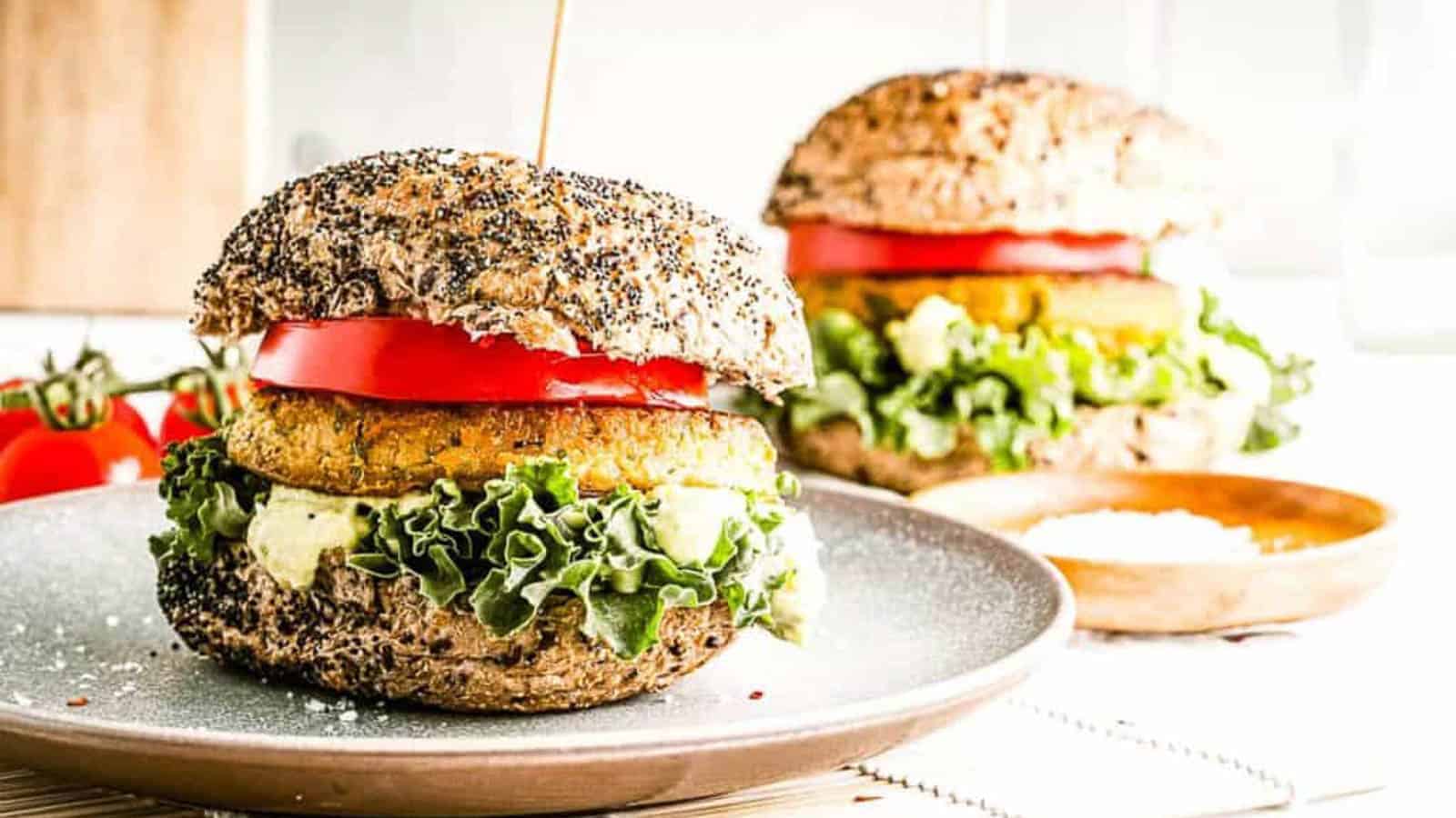 Low angle shot of 2 chickpea burgers on seeded buns with all the fixings.