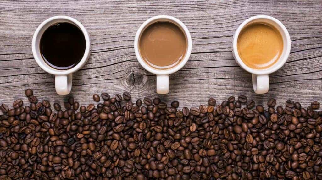 Three cups of coffee on a wooden table.