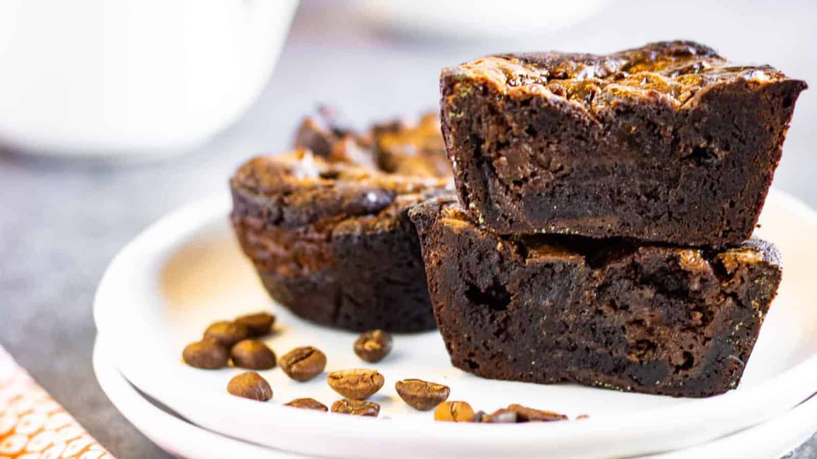 Coffee brownies for two on a stack of two white dessert plates with some coffee beans on the plate.