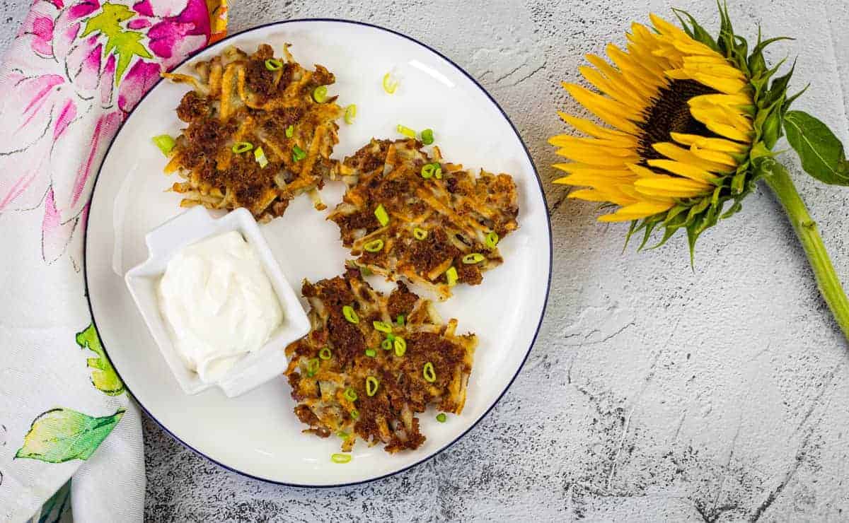 Corned Beef Fritters on a white plate with a sunflower nearby.