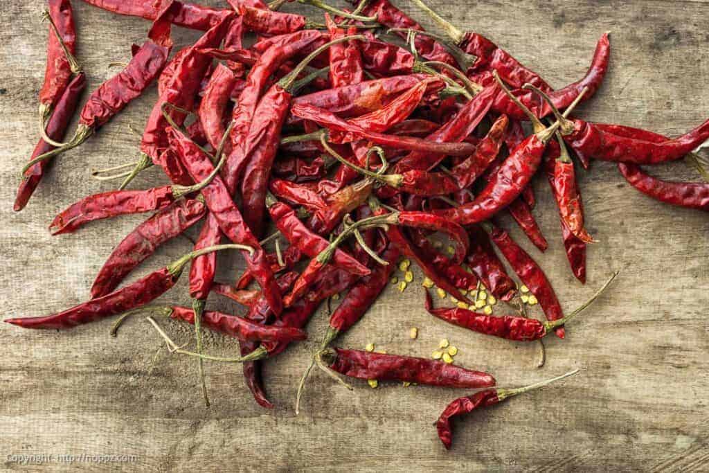 A pile of red chili peppers on a wooden table.