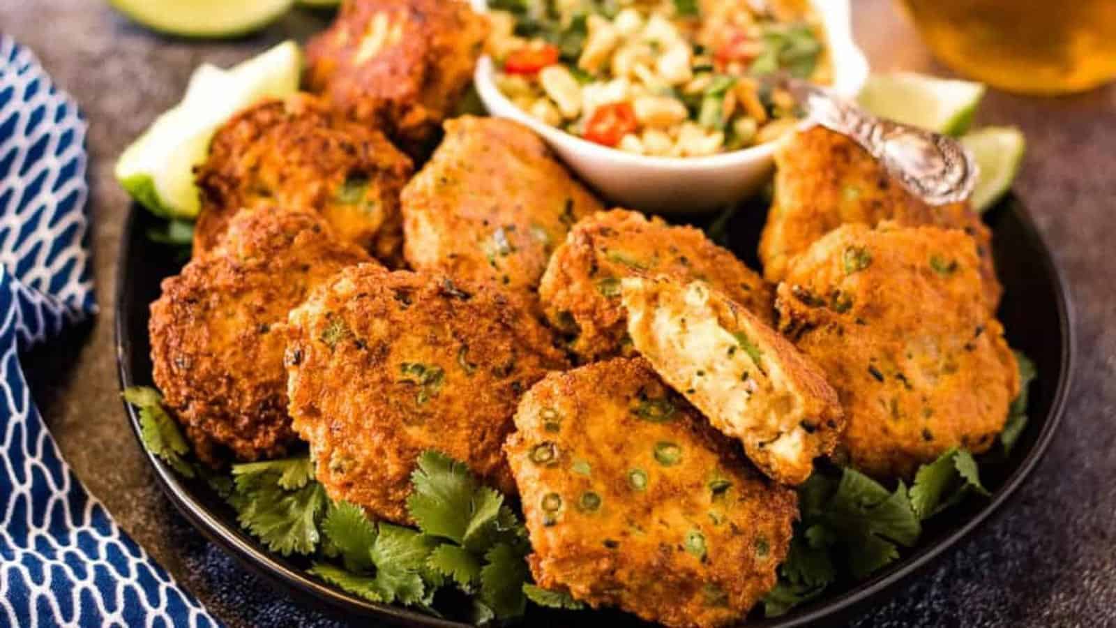 Thai fish cakes on a black plate with prik nam pla.