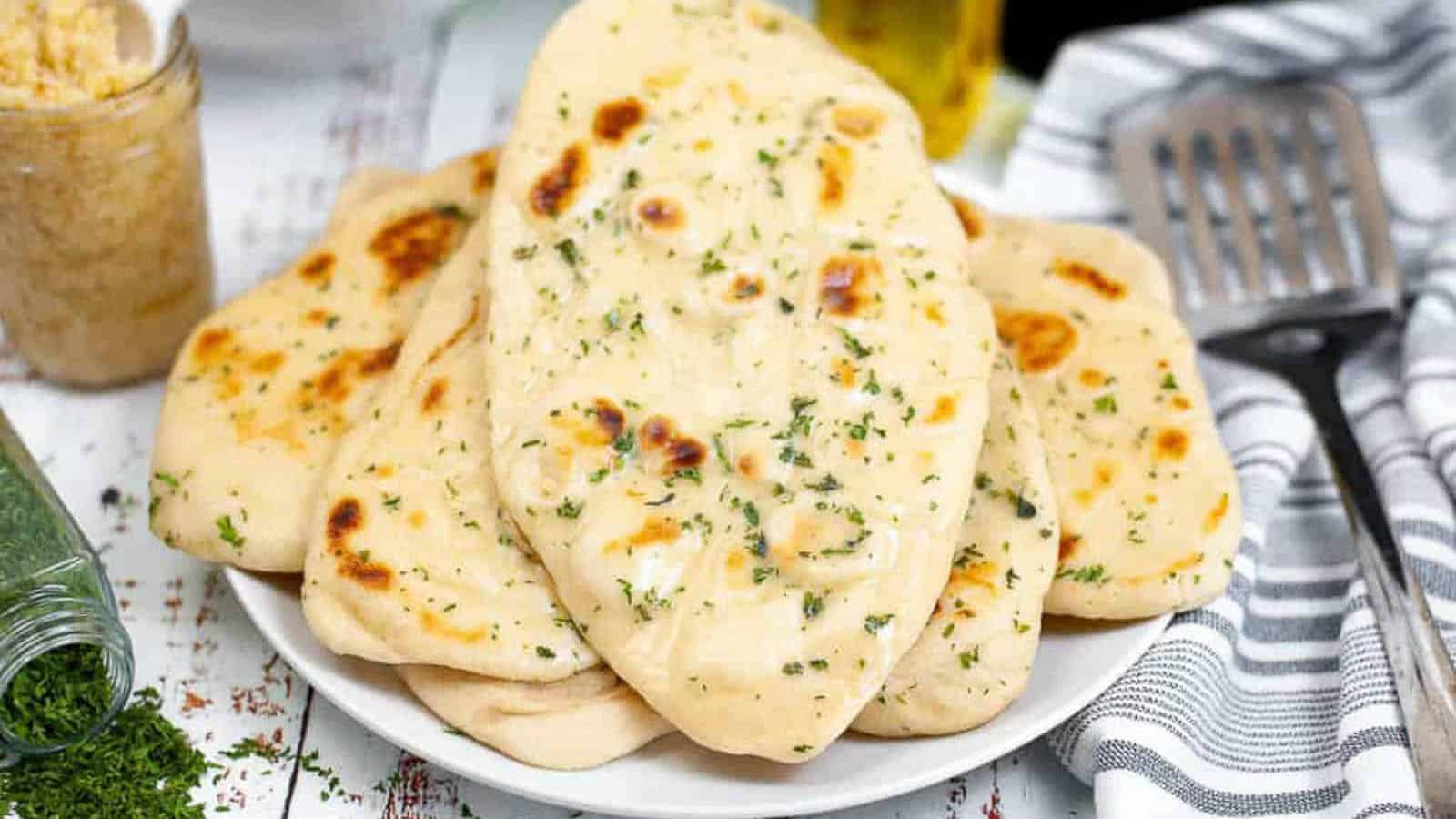 Low angle shot of a pile of garlic butter naan on a plate.