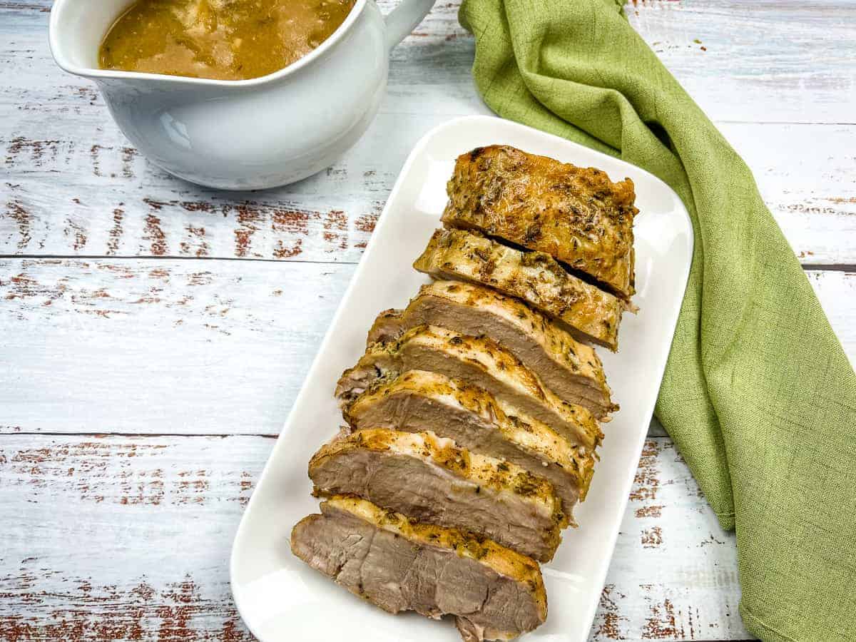 German Pork Loin on a platter with a gravy boat nearby.