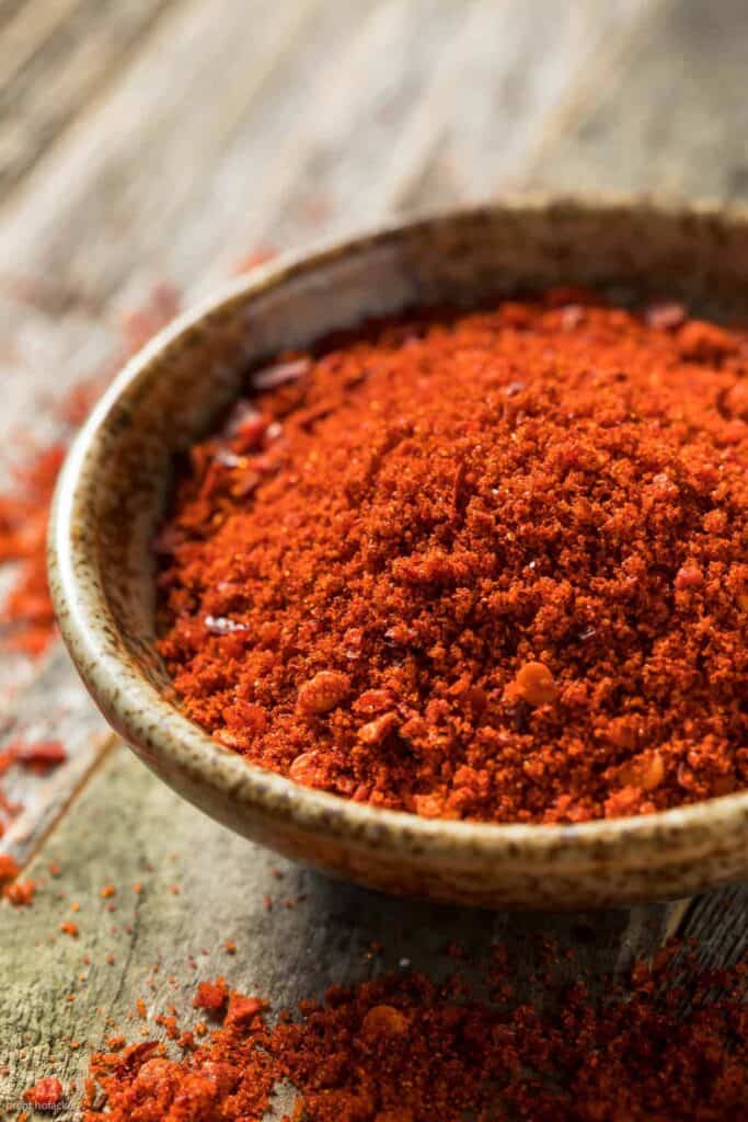 Chili powder in a bowl on a wooden table.