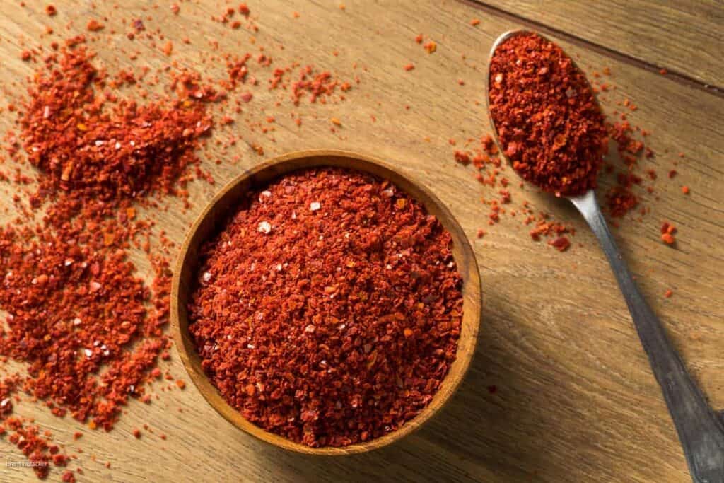 Chili powder in a bowl on a wooden table.