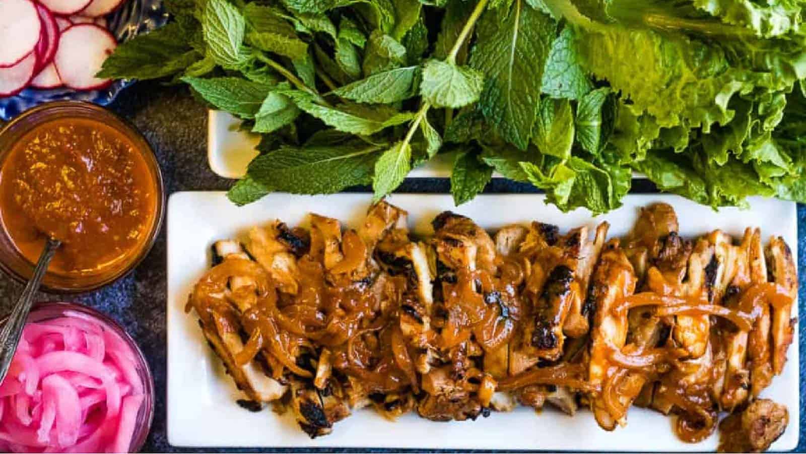 overhead shot of gochujang chicken with herbs and lettuce.