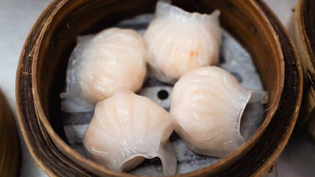 Steamed dumplings in a bamboo basket on a table.