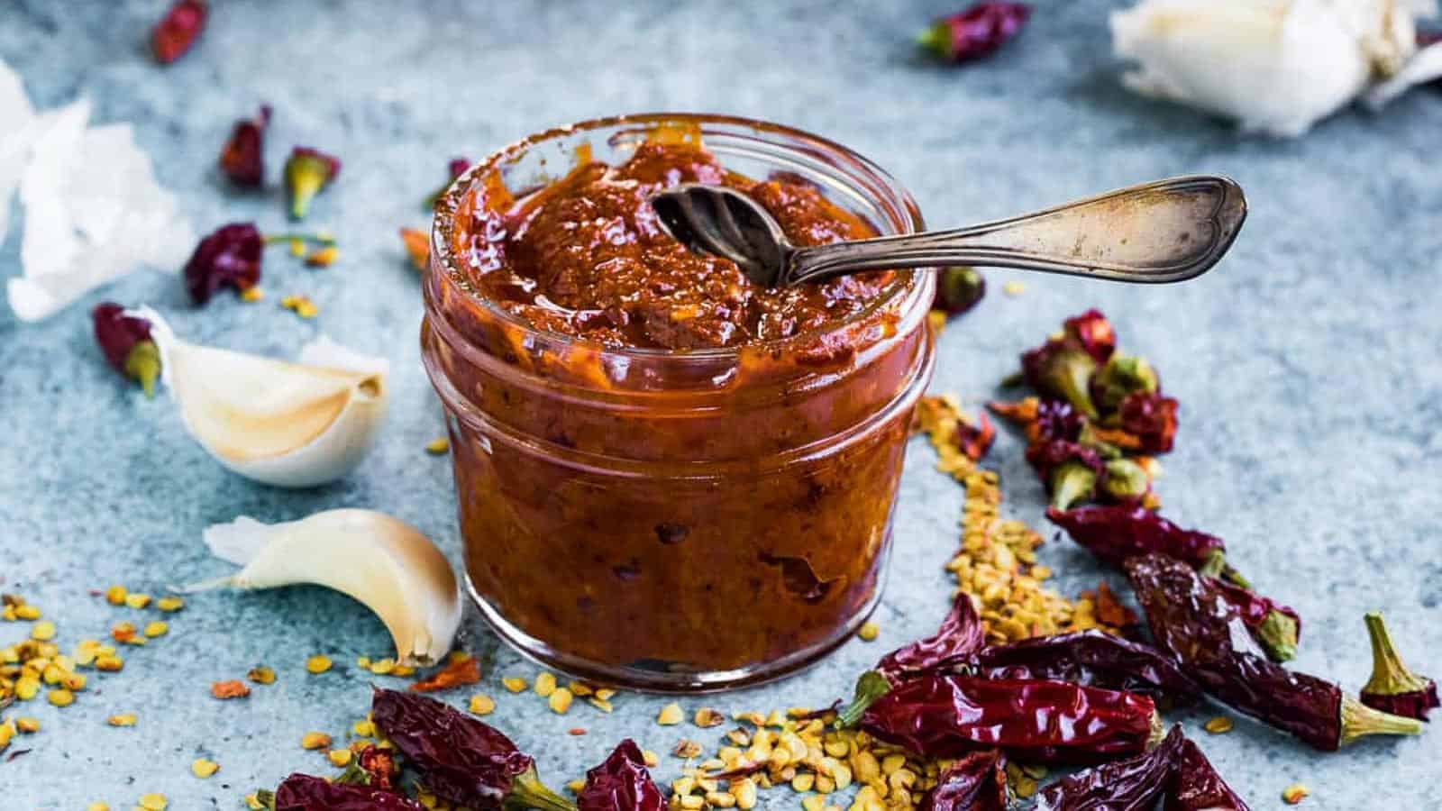 Low angle shot of a jar of harissa paste with a spoon.