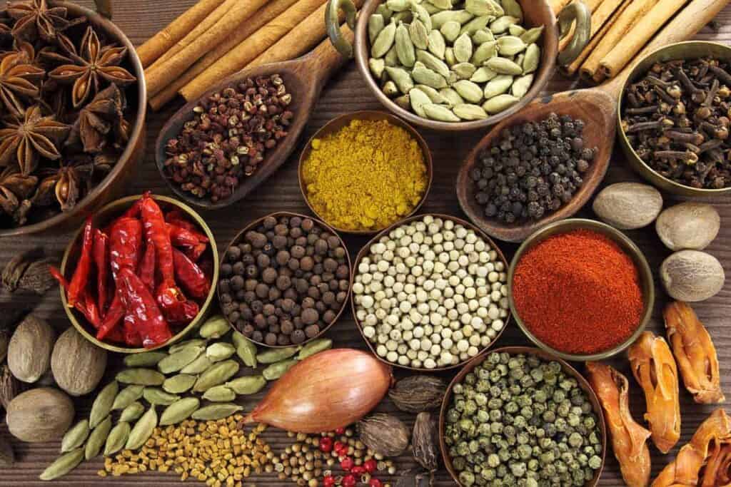 A variety of spices are arranged on a wooden table.