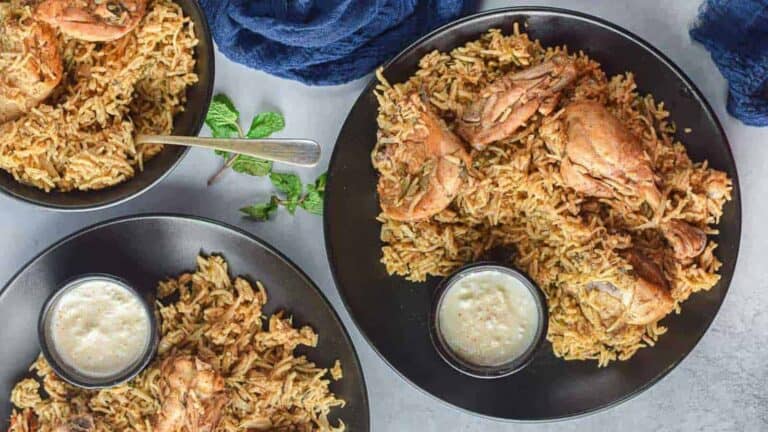 Overhead shot of 3 plates of chicken biryani.