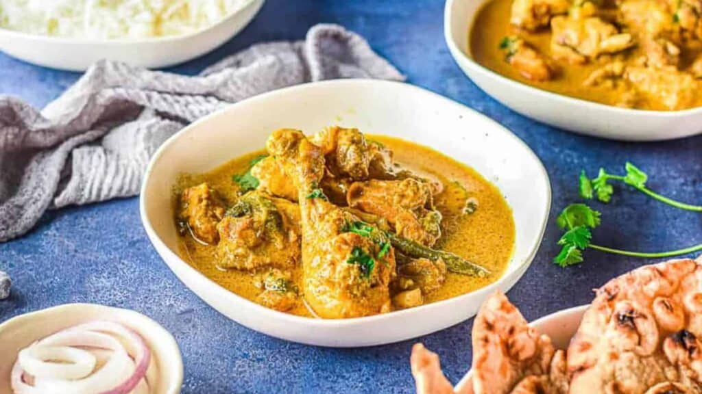 A bowl of chicken curry with rice and naan.