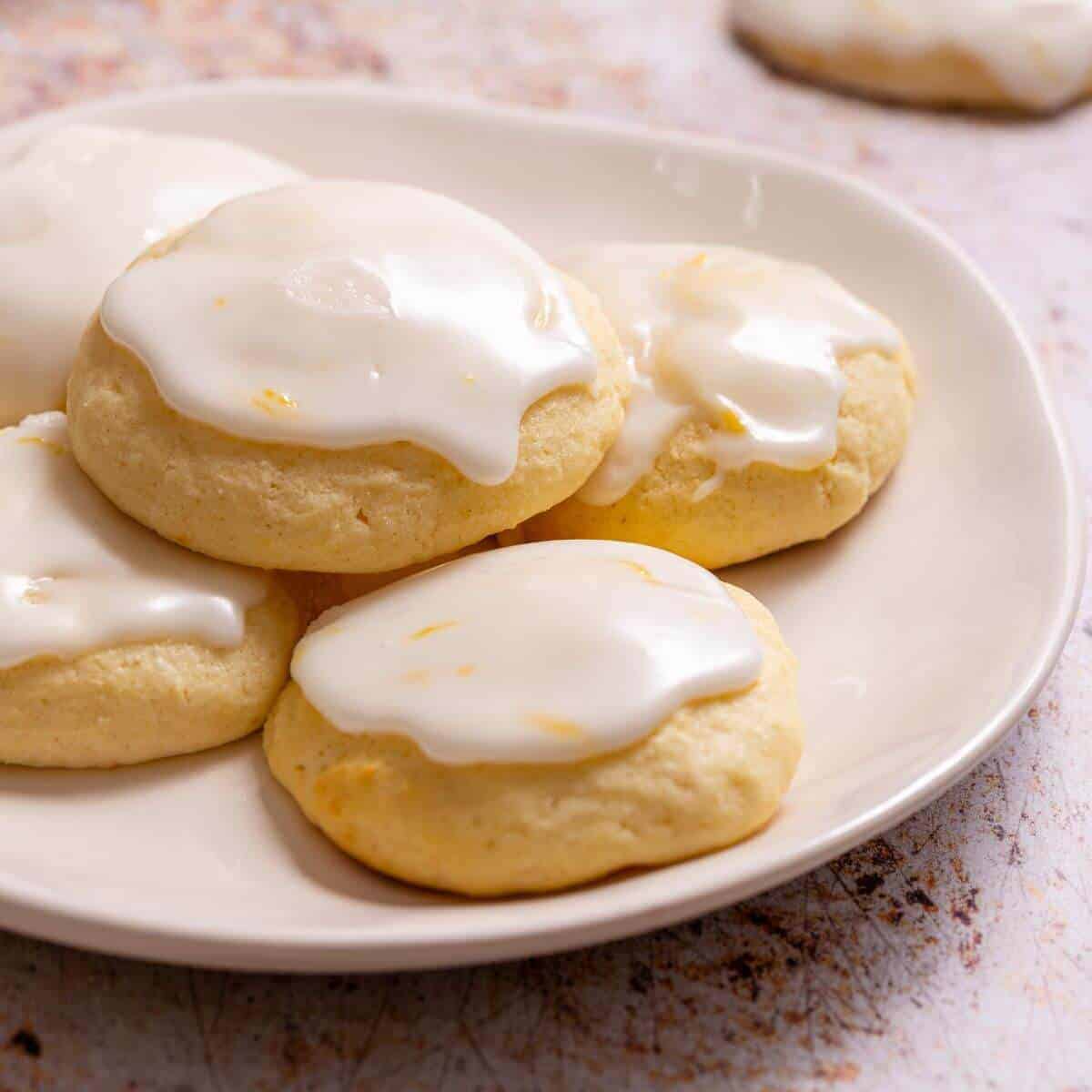 Lemon ricotta cookies on rack with icing bowl.