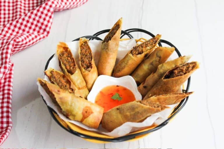 Vietnamese spring rolls in a basket with dipping sauce.