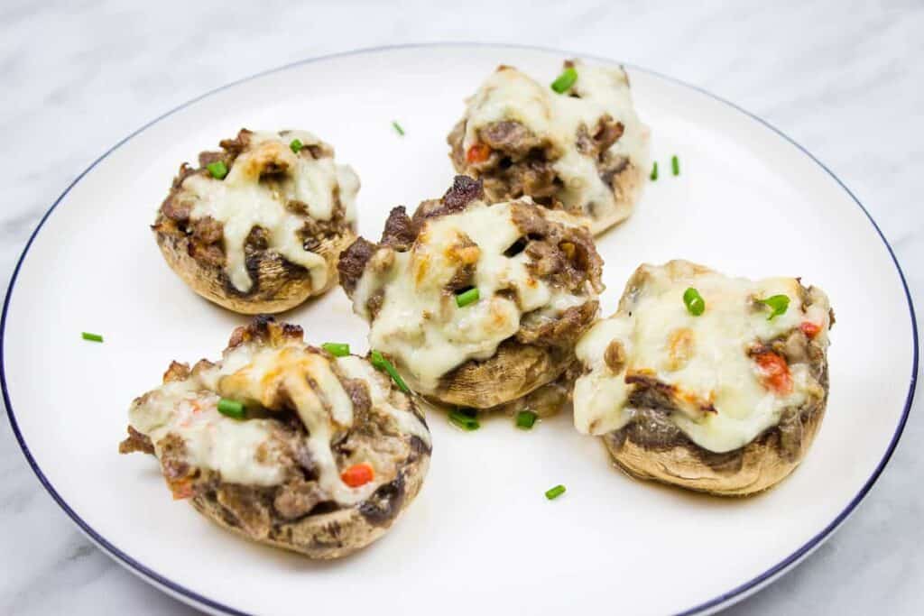 Four stuffed mushrooms on a white plate.