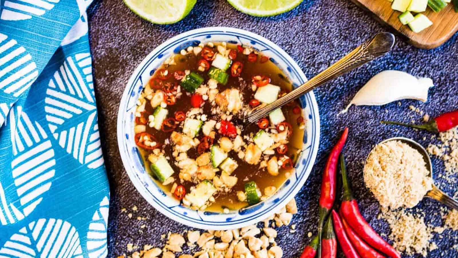 Overhead shot of Prik Nam Pla dipping sauce with limes and peanuts on the side.