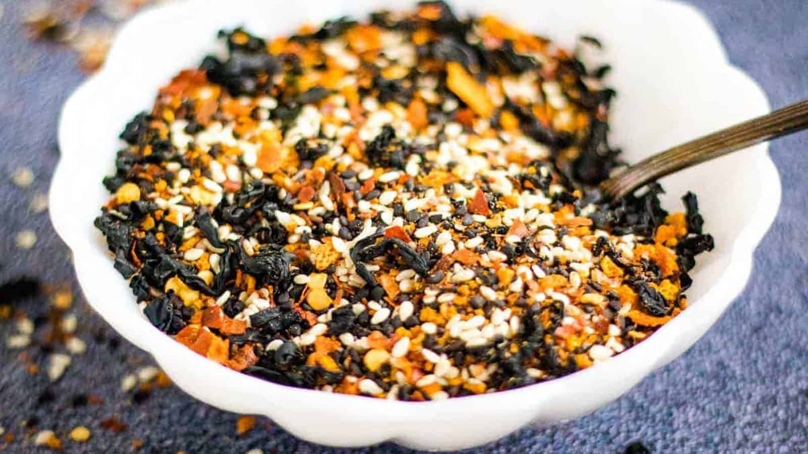 Low angle shot of a white bowl filled with shichimi togarashi with a spoon in it.