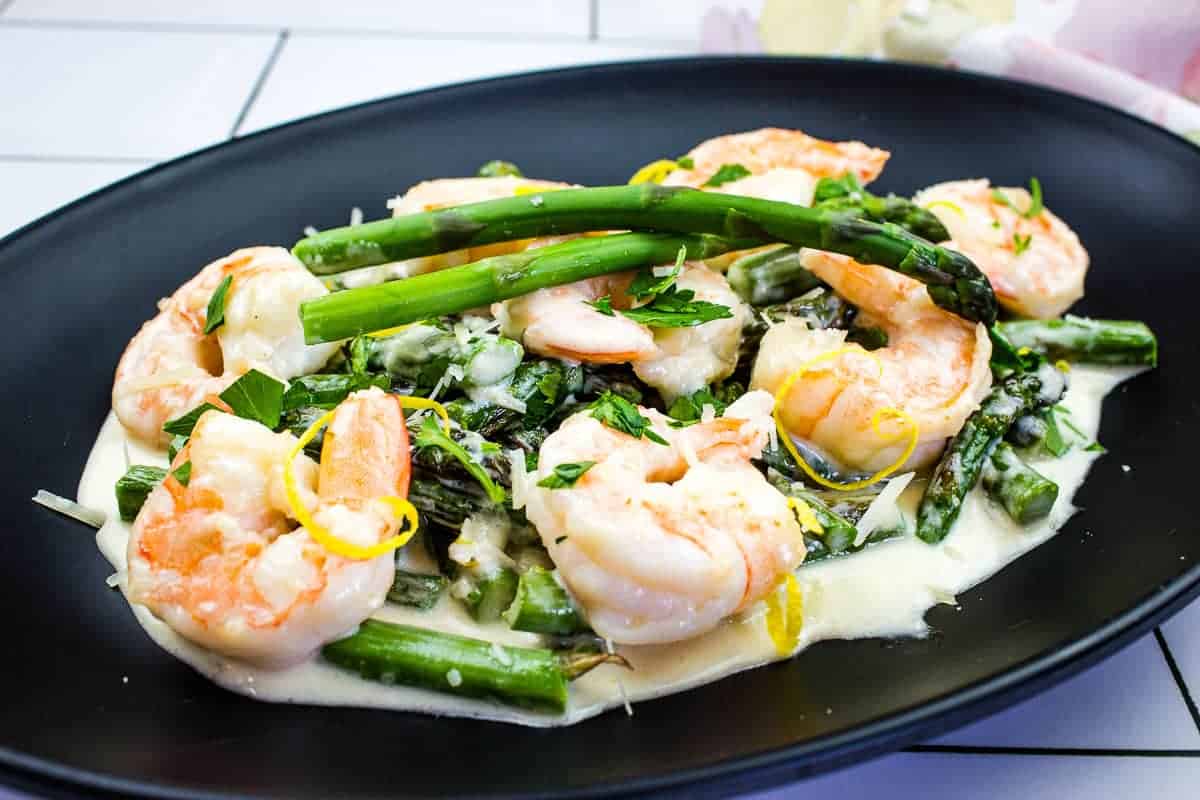 Shrimp & Asparagus Alfredo on a black plate.