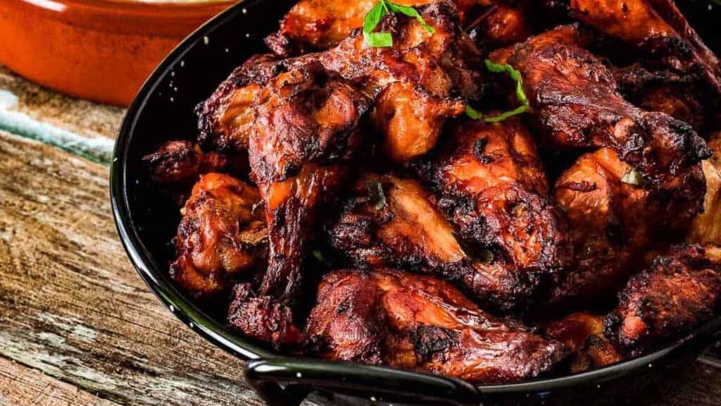 A plate of tandoori chicken with a side dish of cooked rice, shot from a low angle.