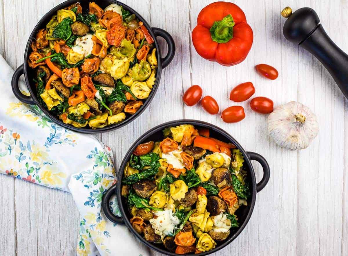 Two large bowls of tortellini with meatballs on a counter.