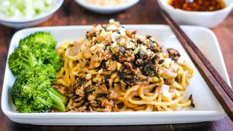 Low angle shot of a plate of vegetarian dan dan noodles with broccoli.