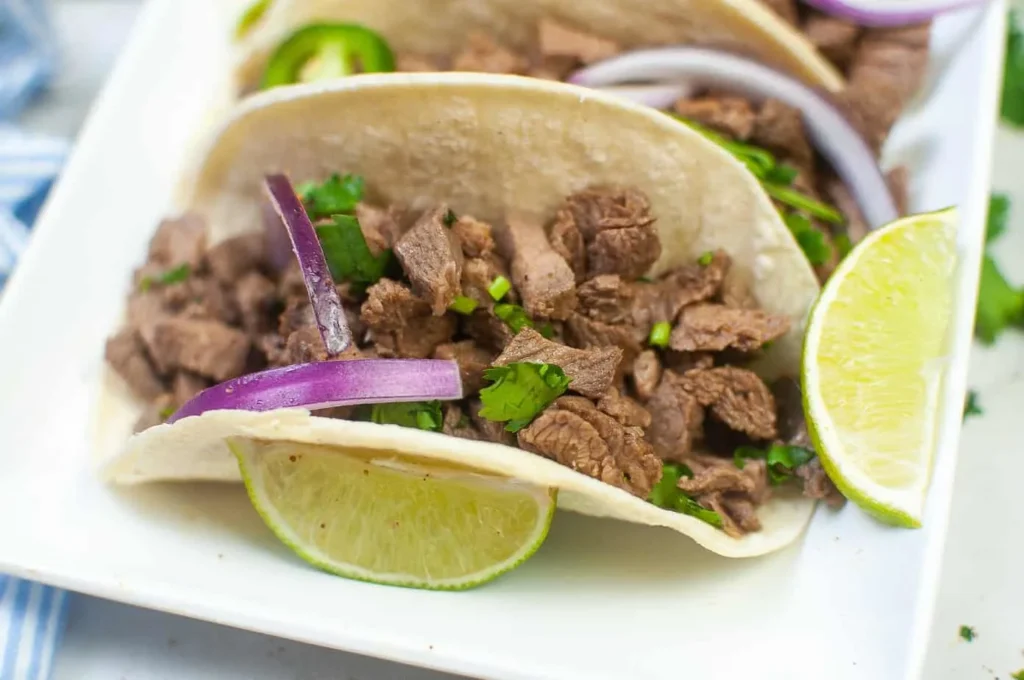 White plate with a street taco and limes.