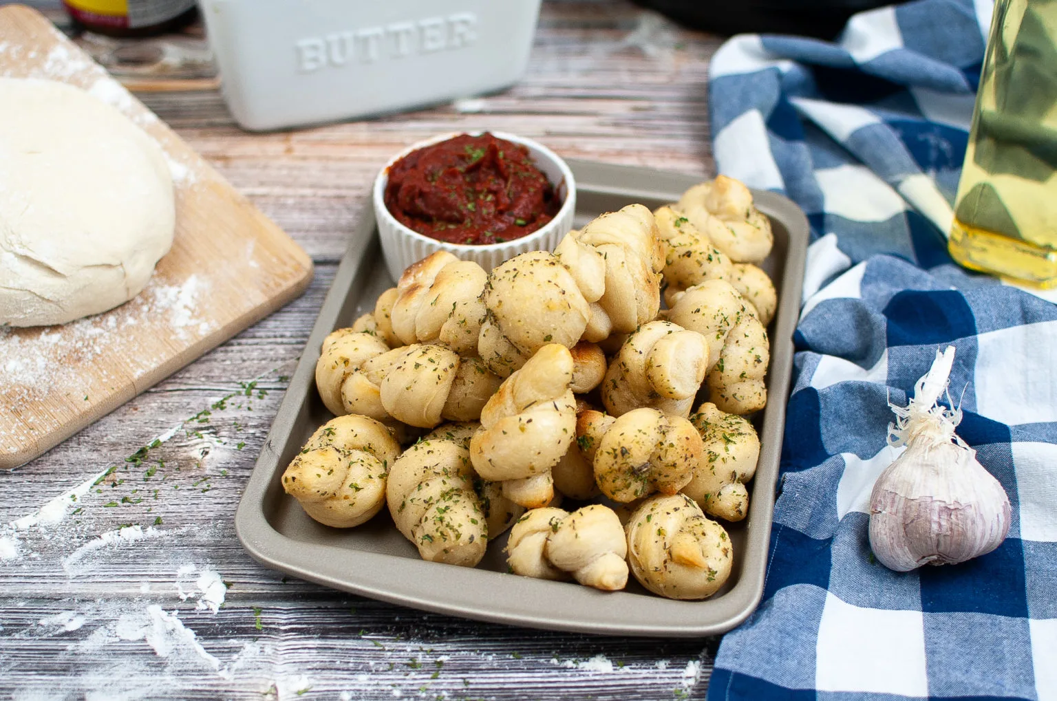 Pan of garlic knots with marinara sauce.