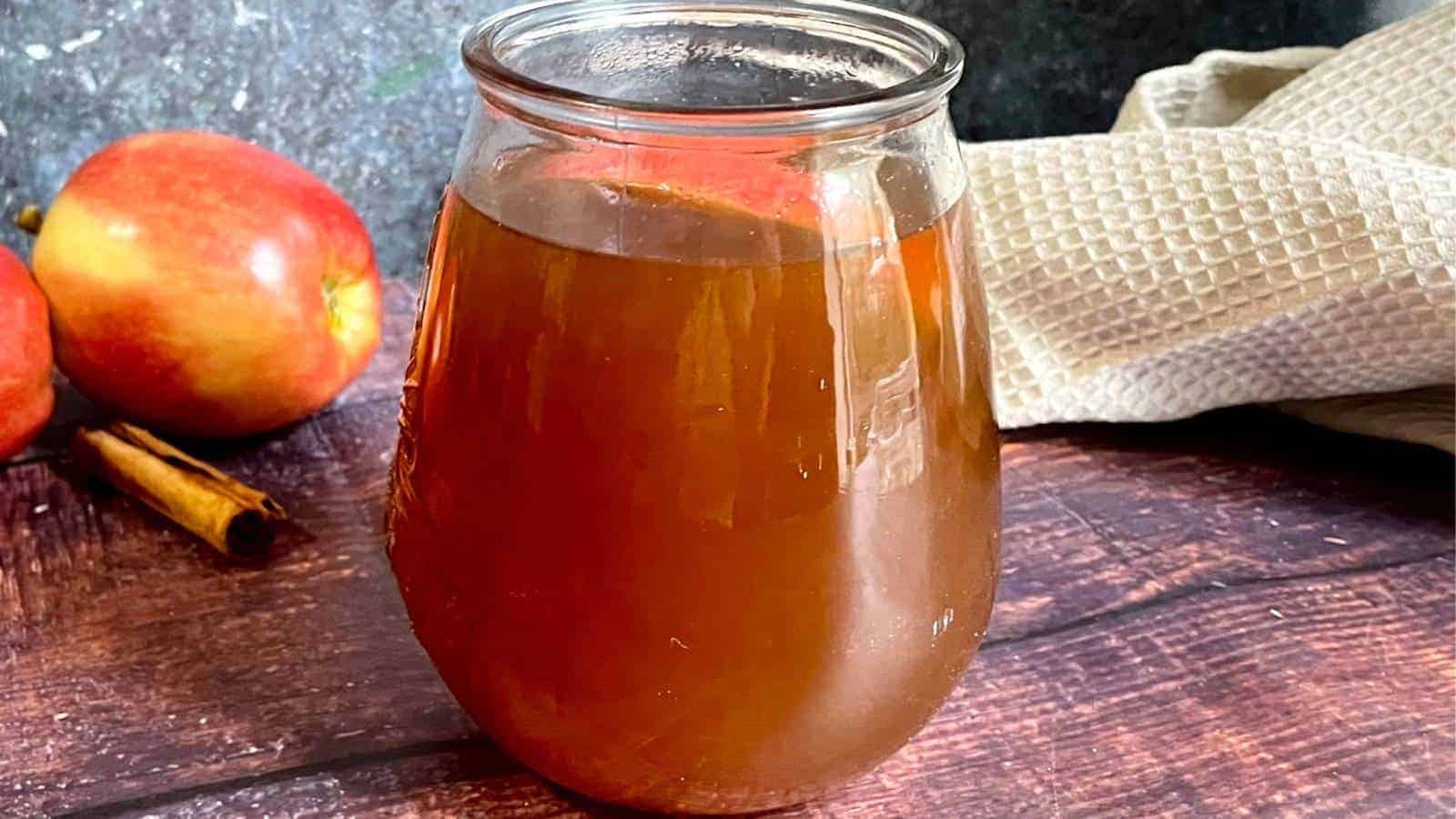 A jar of apple cider on a wooden table.