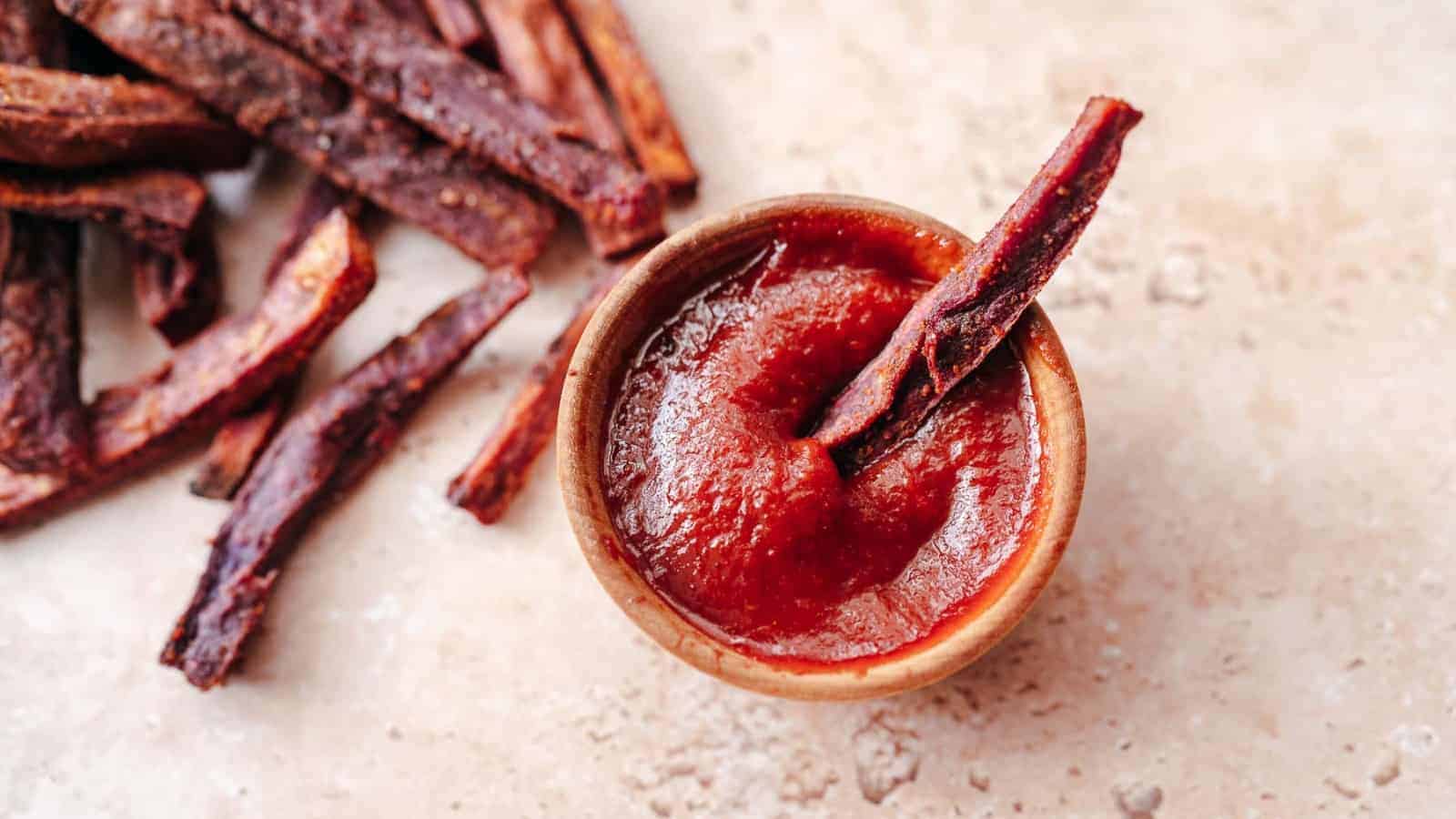 A bowl purple of fries paired with a side of red sauce.