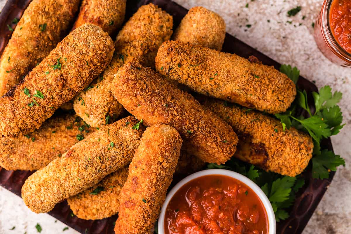 Chicken mozzarella sticks on a platter with marinara dip.