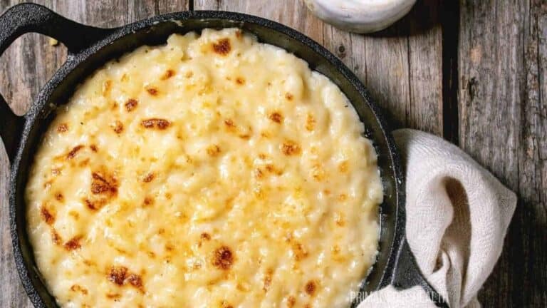 Cheesy macaroni and cheese in a skillet on a wooden table.