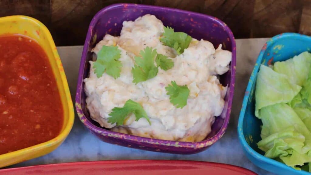 Three colorful bowls of dip with lettuce and tomatoes.