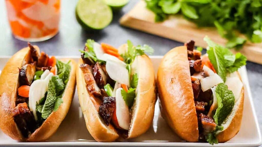 Three vietnamese sandwiches on a white plate.