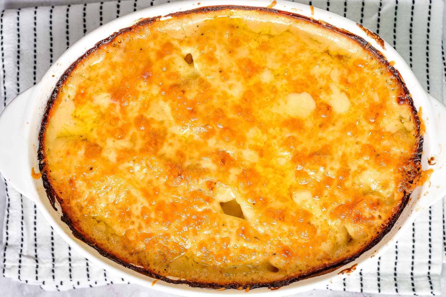 Overhead shot of potatoes au gratin cooked in an oval baking dish.