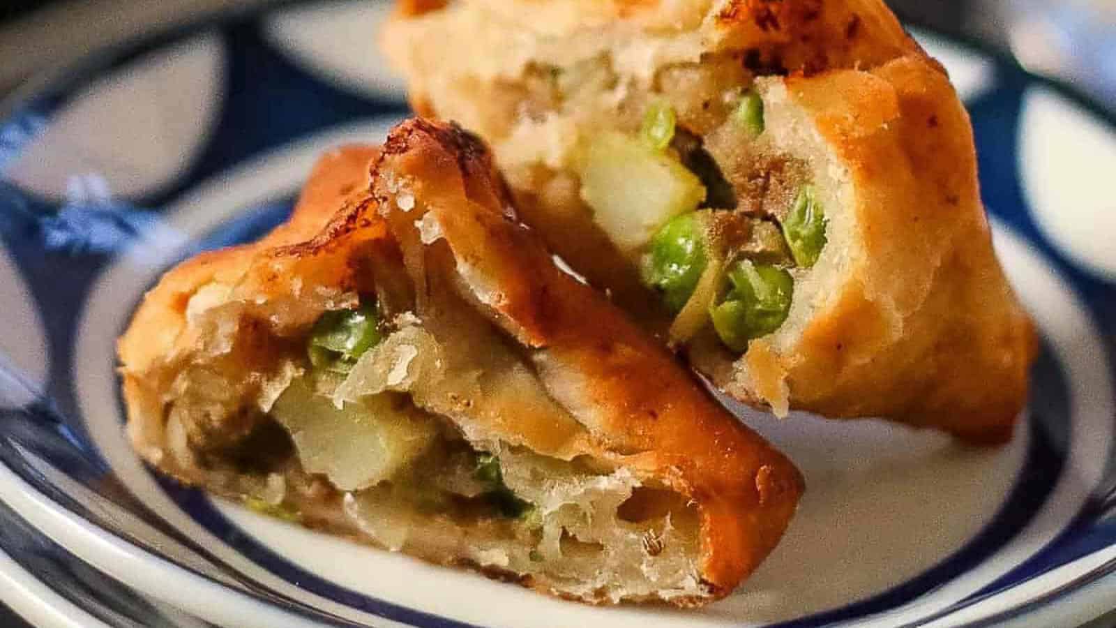 Low angle shot of a samosa cut in half so that you can see the potato filling inside.