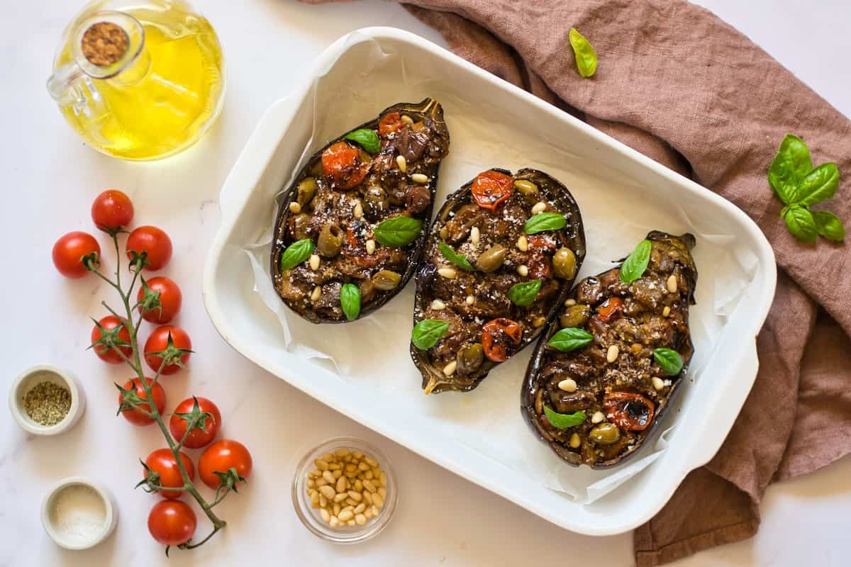 Cooked stuffed eggpant in a casserole dish.