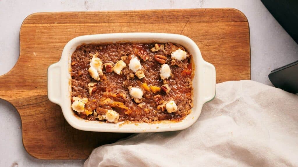 A white dish with a baked dessert on top of a cutting board.