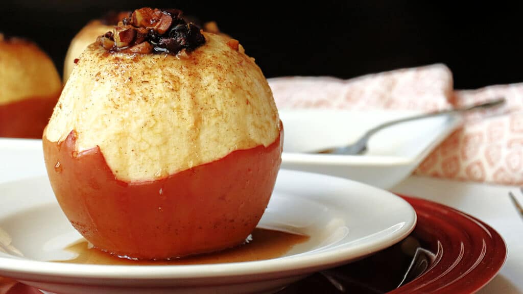 Apples stuffed with caramel and pecans on a plate.