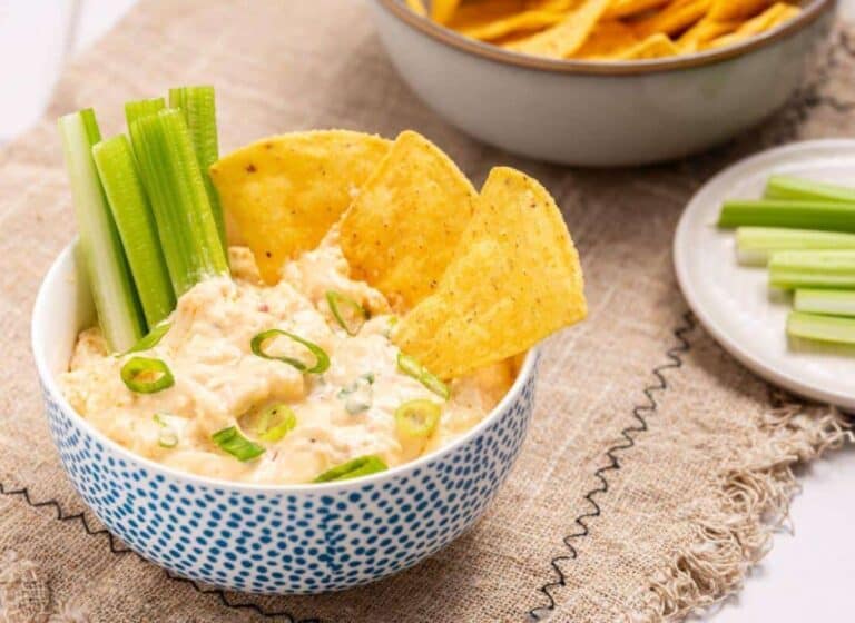 A bowl of buffalo chicken dip with celery and chips.