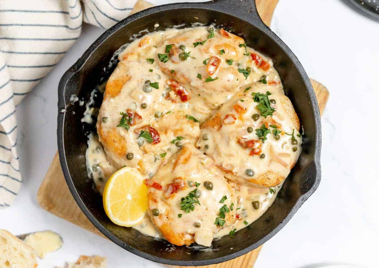 Creamy chicken in a cast iron skillet with capers. 